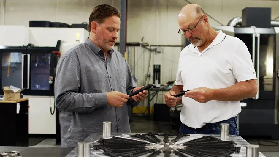 Allegiance Mold, LLC president and CEO Ted Stender and senior mold designer Dave VanDeLaare inspecting final parts from plastic injection mold designed and manufactured using Cimatron® software