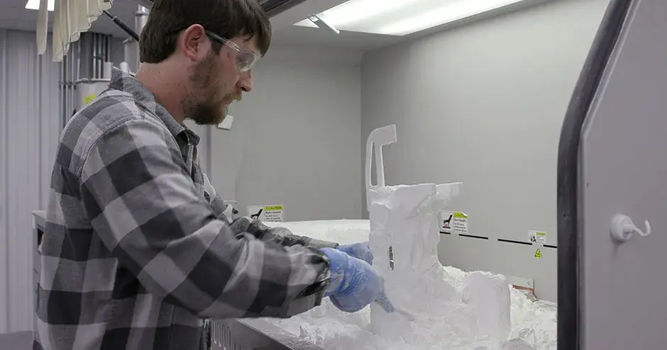 A person dusting off an SLS 3D printed part 
