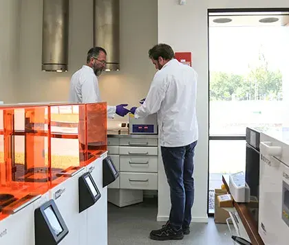 a person in a dental lab surrounded by 3D printers and lab equipment
