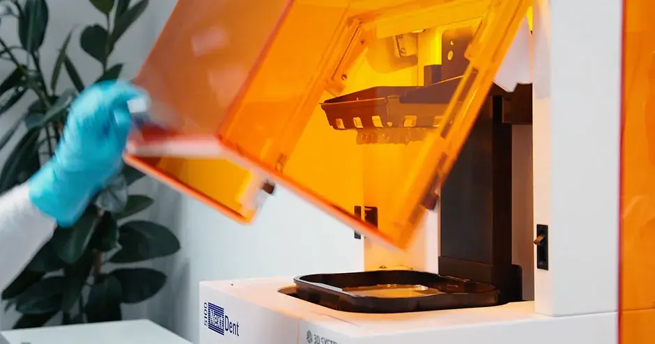 a 3D Dental Printer opening up with dental parts in a tray