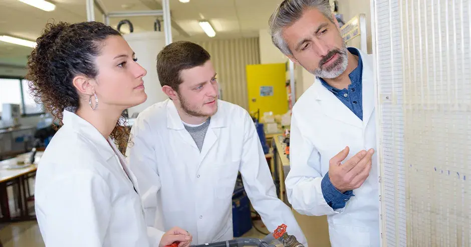 3 people standing in a facility discussing work