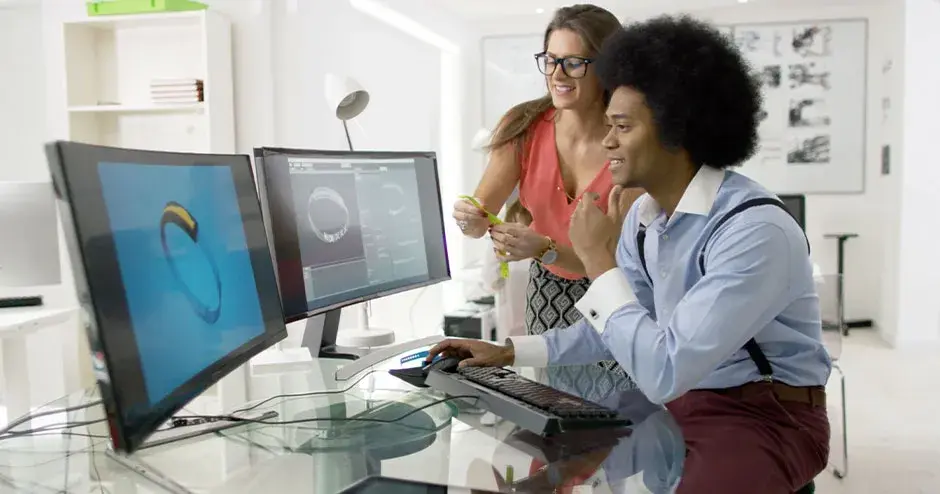 2 people designing a watch and editing the file on a large monitor