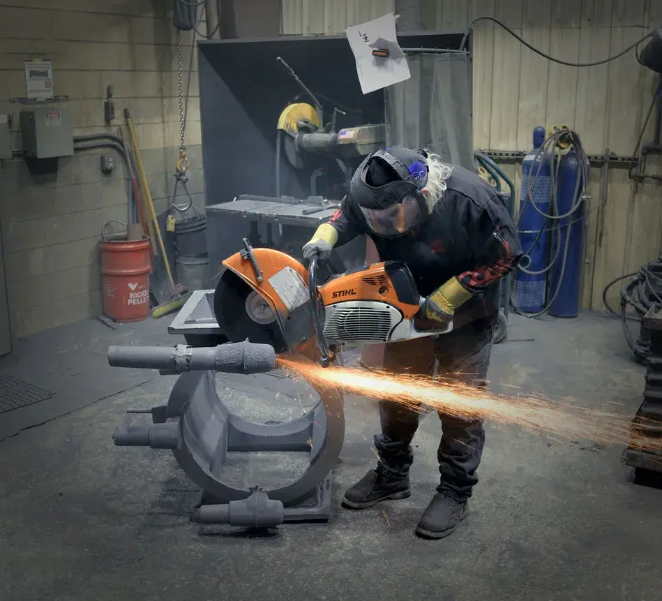An Astech employee cuts gating from the cast pump casing. 