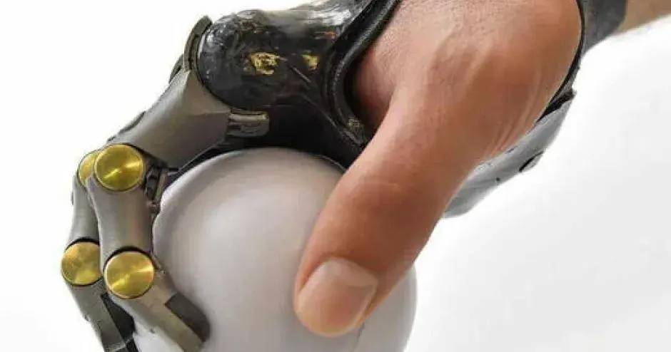 Hand with a metal 3D printed partial prosthetic holding a white ball